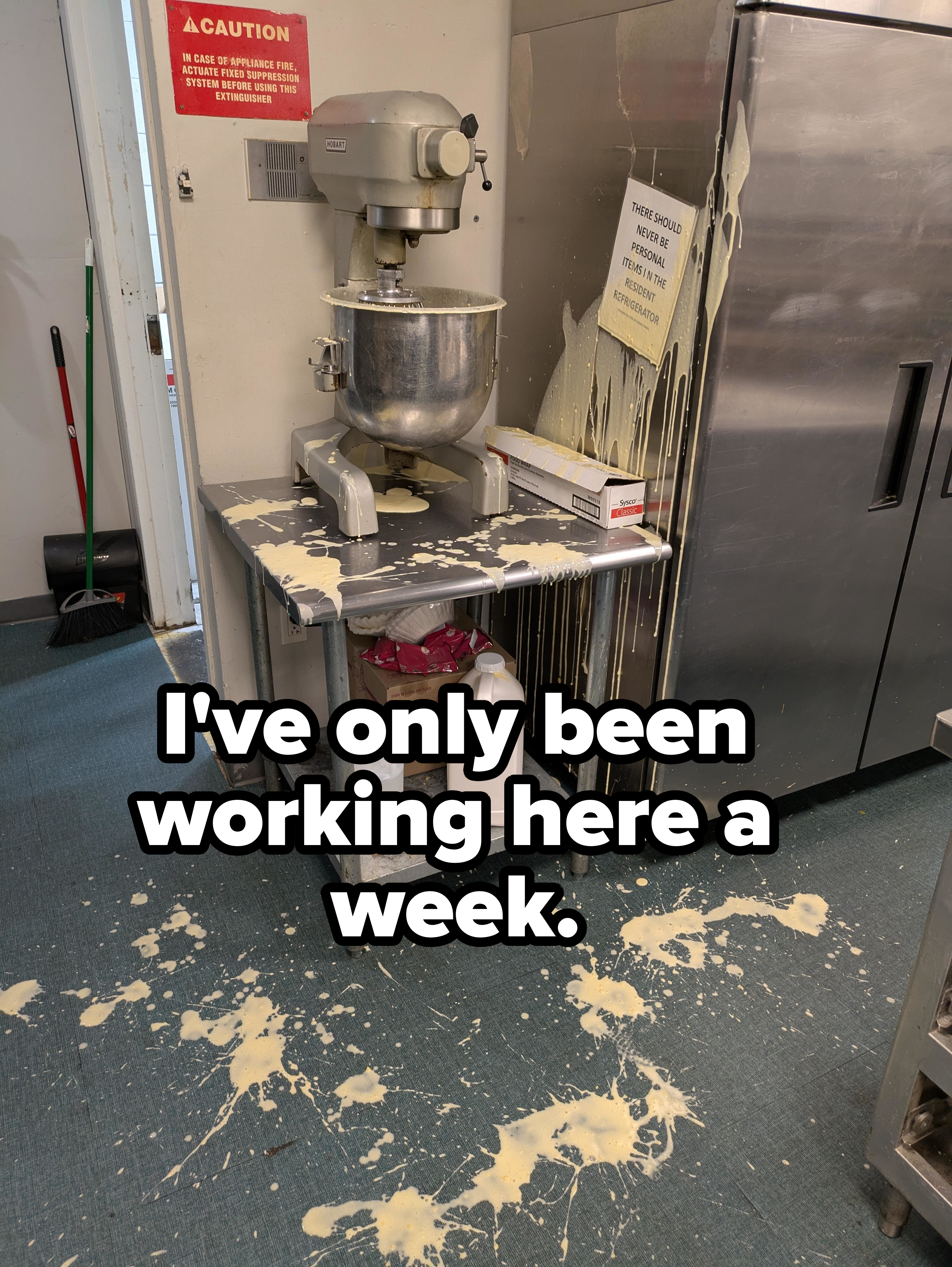 Mixer overflowed with batter, spilling onto a kitchen floor with batter splatters. Nearby signs are visible but text is not readable