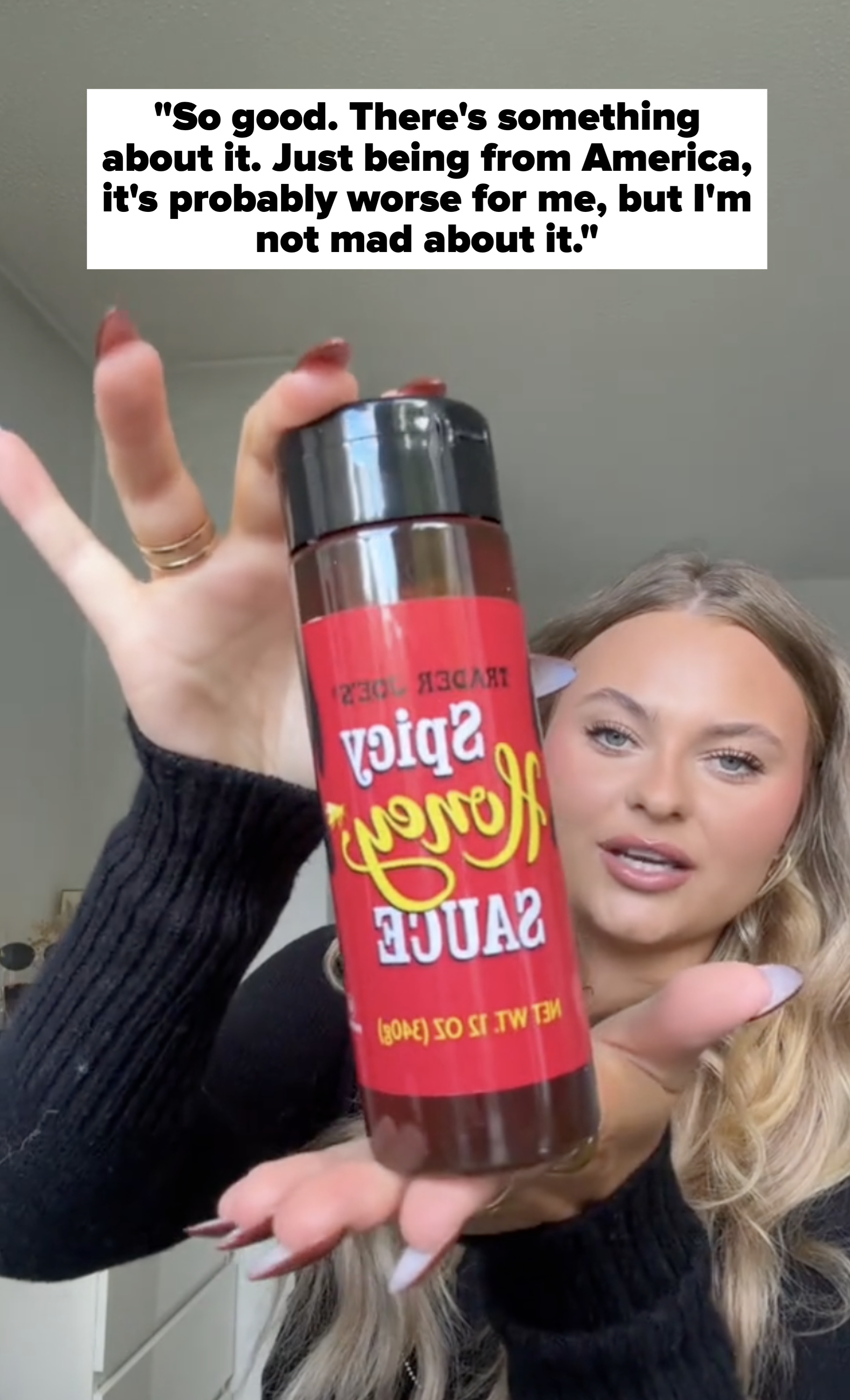 Person holding a bottle of Trader Joe&#x27;s Spicy Honey Sauce, angled toward the camera