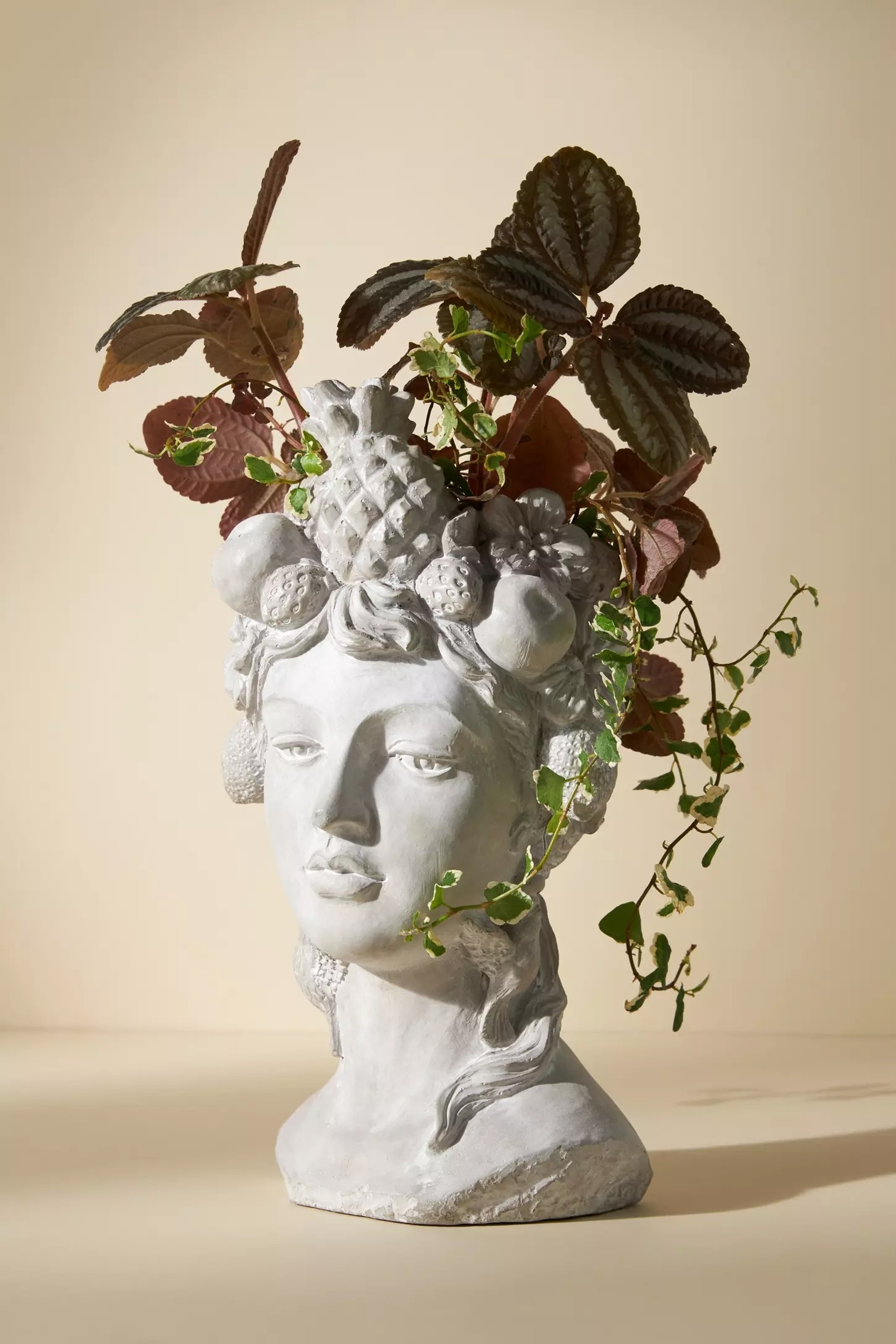 Bust-shaped planter with ivy and foliage on top, resembling hair, featured in a shopping article