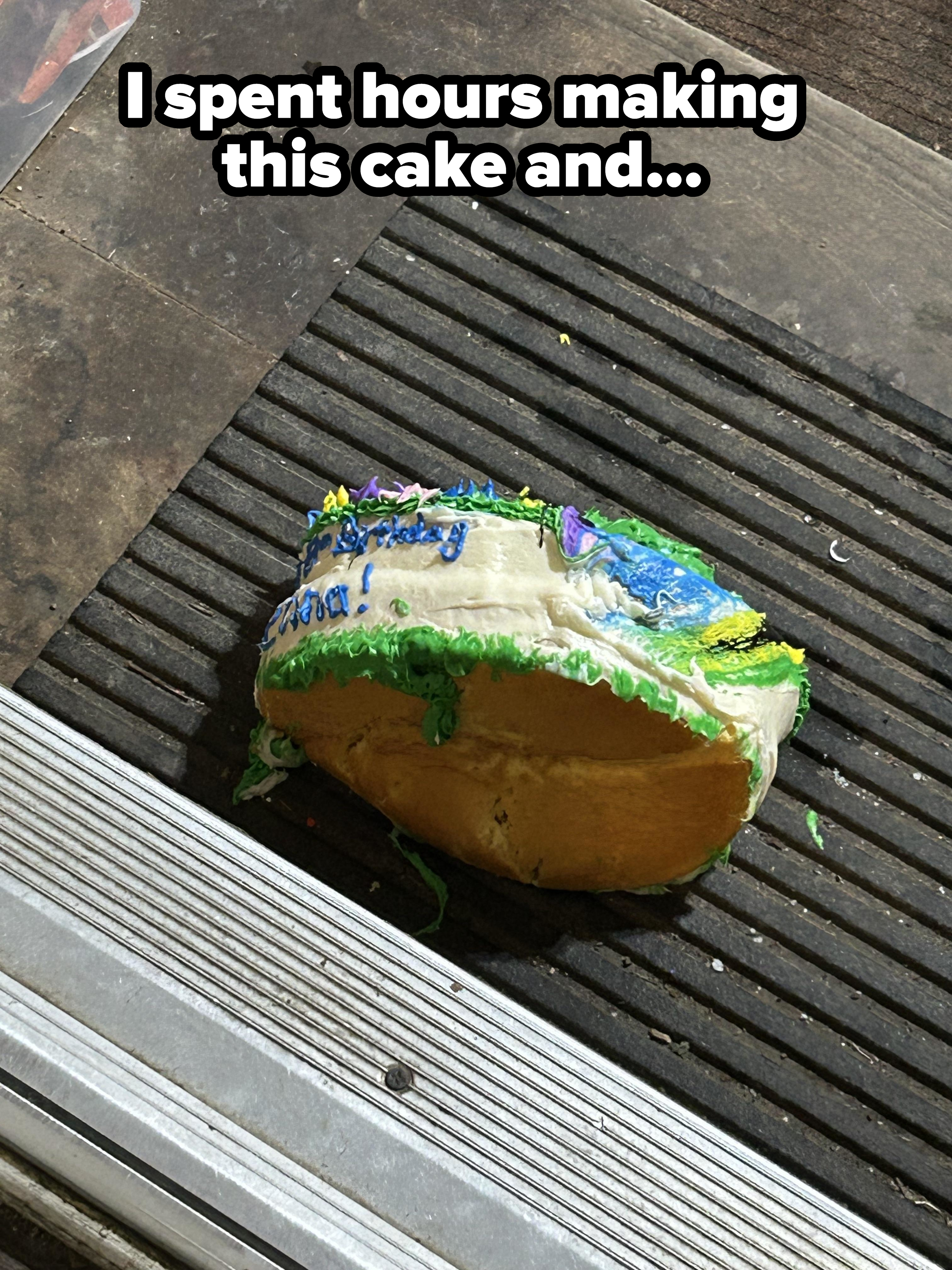 A smashed cake on a doormat, partially showing blue icing and a message, likely dropped