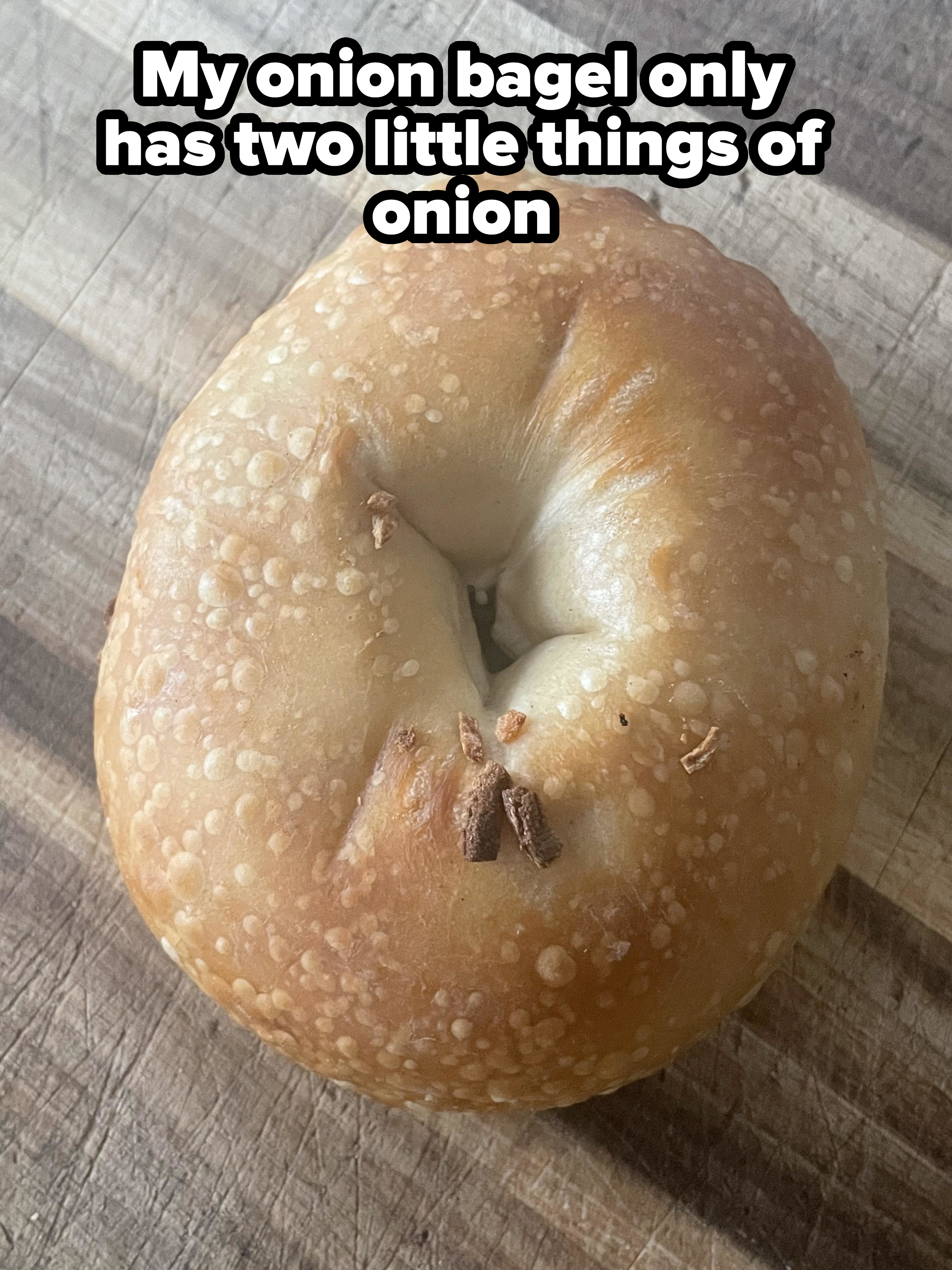 A plain bagel with a slightly browned, textured surface on a wooden cutting board