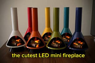Several colorful LED mini fireplaces with faux logs are displayed on a wooden surface. Text reads: "the cutest LED mini fireplace."