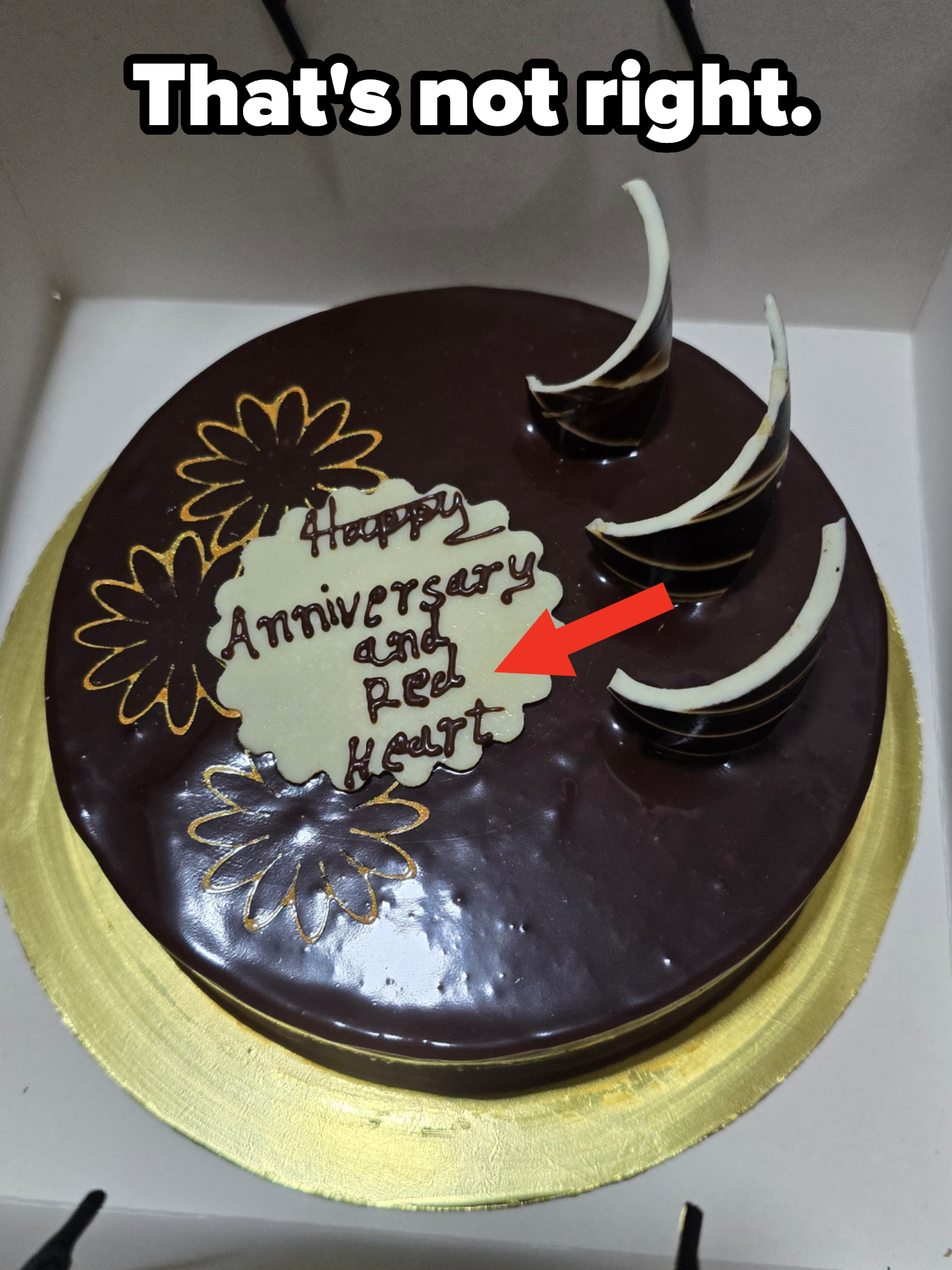 Chocolate cake with flower decorations and text: &quot;Happy Anniversary and Red Heart.&quot; Three crescent-shaped chocolate pieces adorn the cake