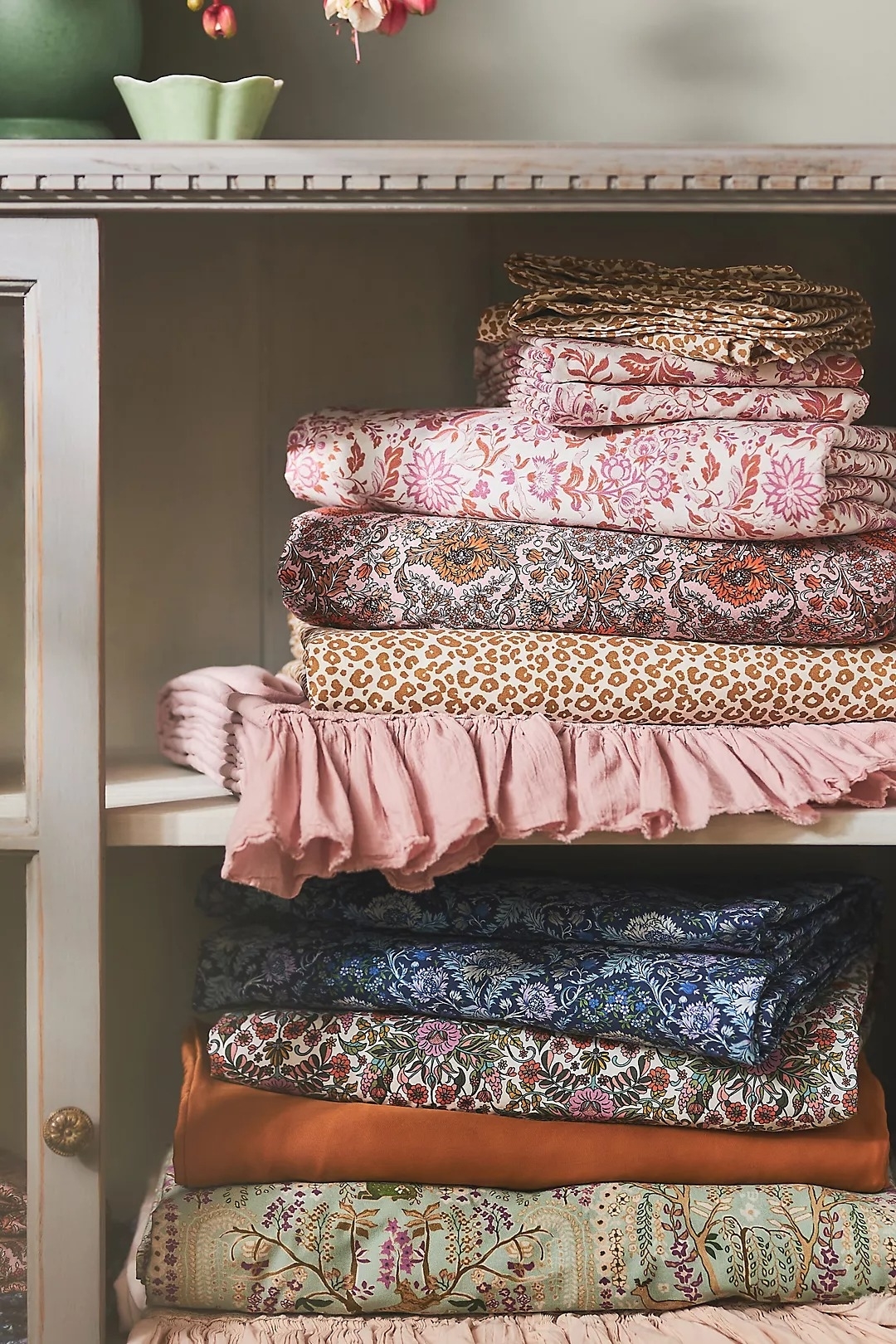 Stack of patterned and textured fabric on a shelf, suitable for home decor or fashion projects