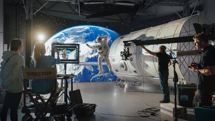 Film crew shoots a space scene on a soundstage with an actor in a spacesuit, illustrating the behind-the-scenes of movie-making