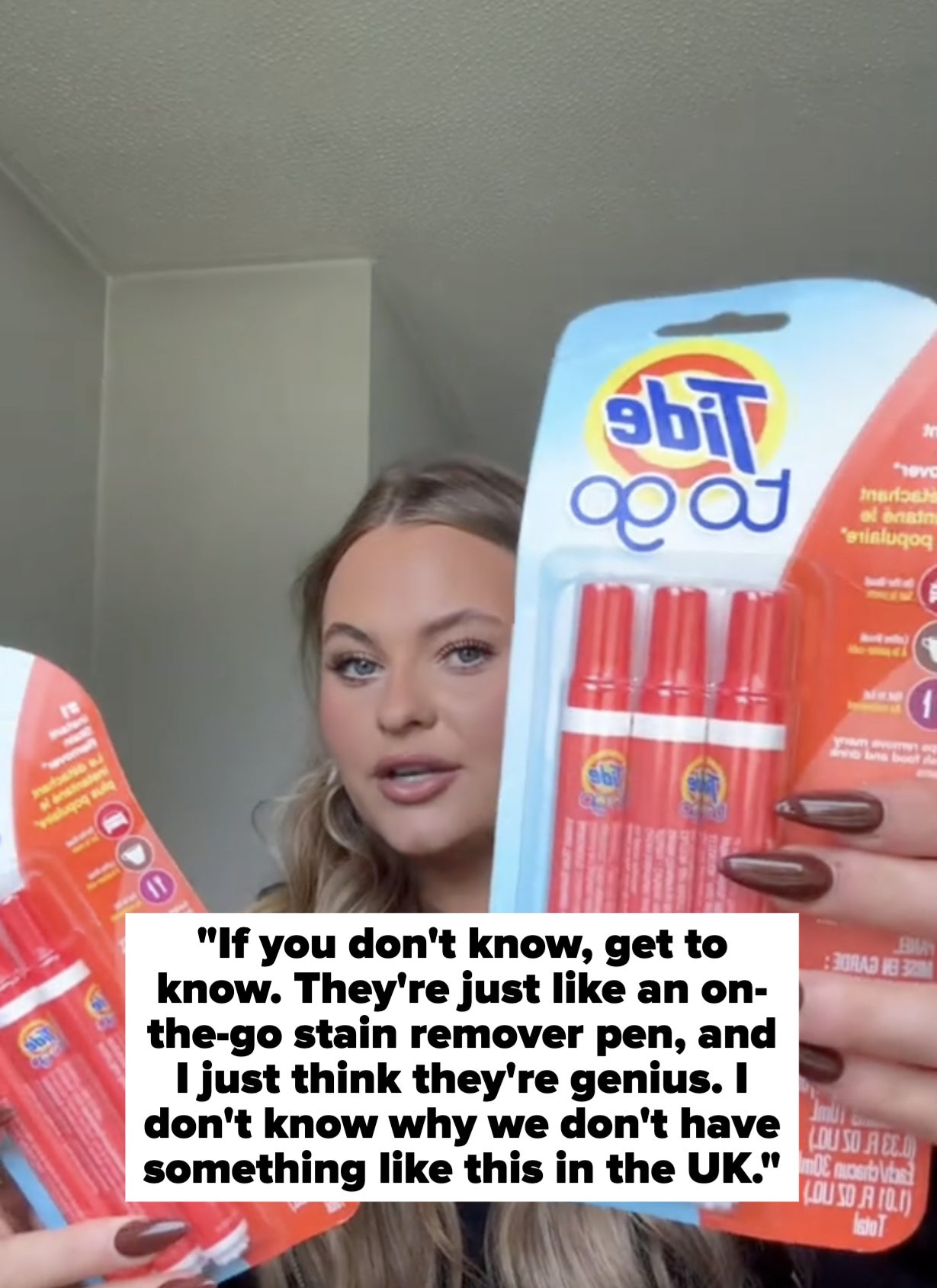 Person holding two Tide To Go stain remover packs, displaying the product to the camera