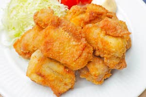 皿に盛られた唐揚げとキャベツ、トマト、レモンで飾られた料理。