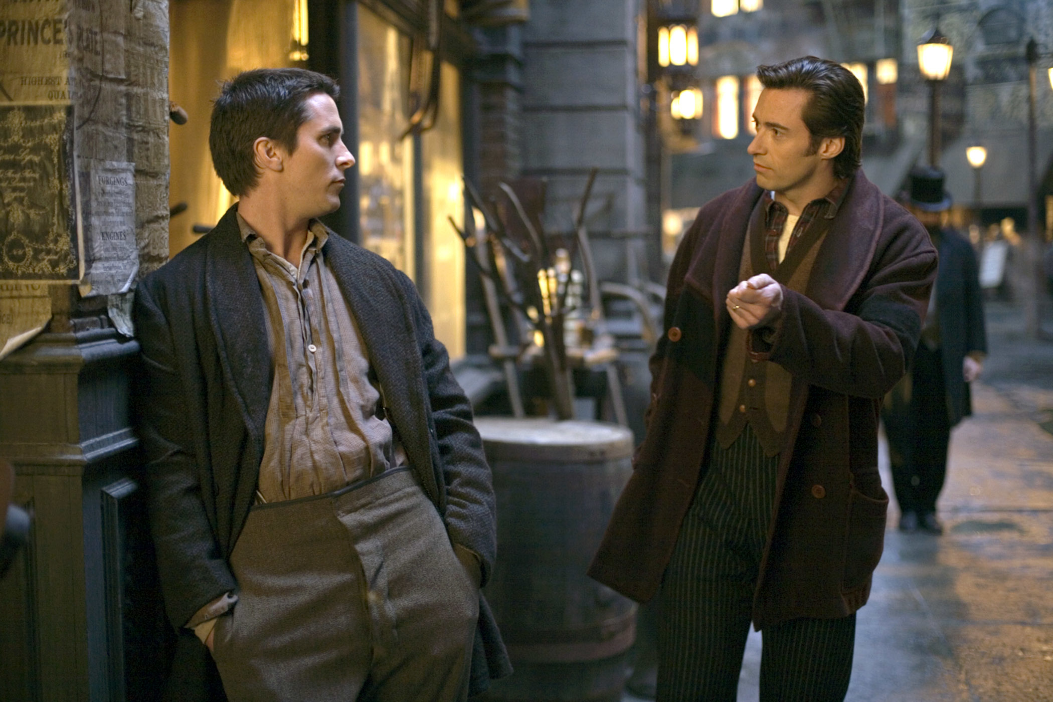 Two men in 19th-century attire, one leaning against a wall, the other gesturing as they converse on a cobblestone street