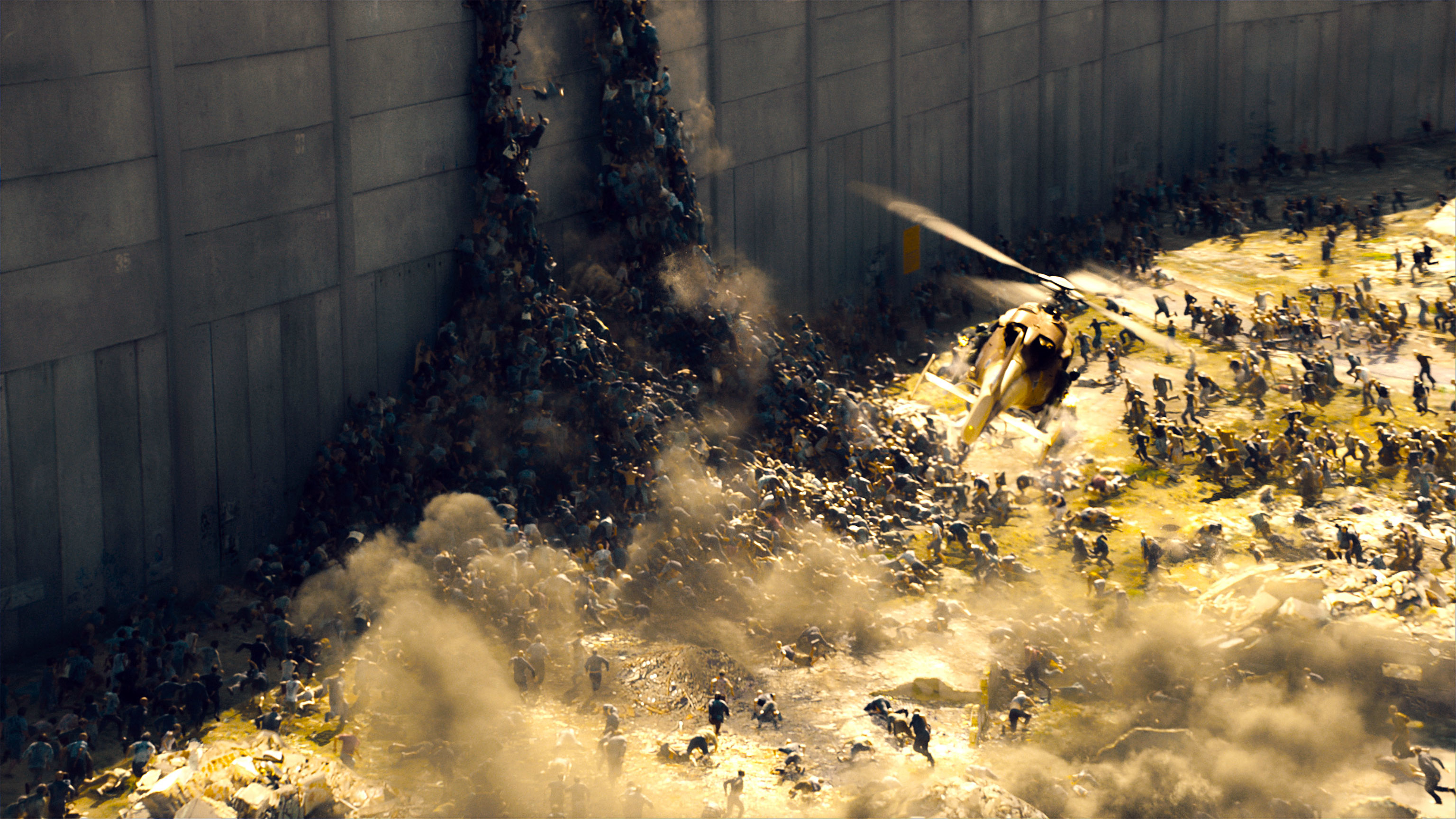 Helicopter flies over a crowd of people climbing a wall, creating a chaotic scene. Dust and debris rise around them