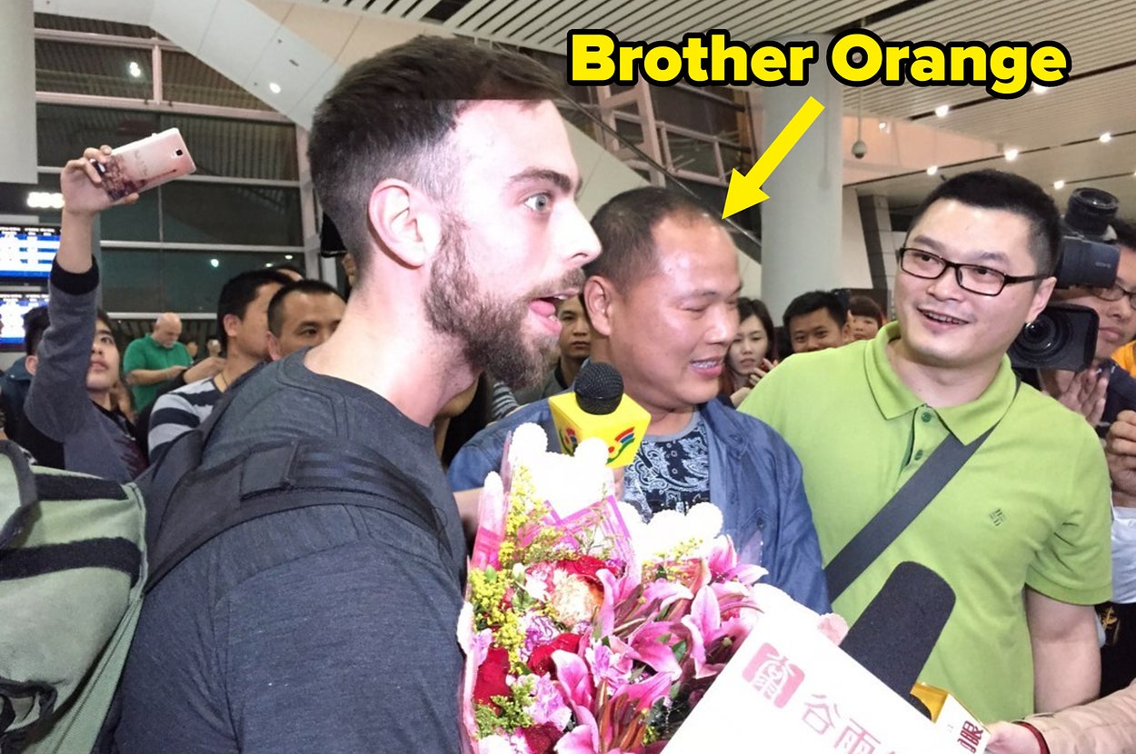Person holding flowers, surrounded by a crowd and media, at an airport