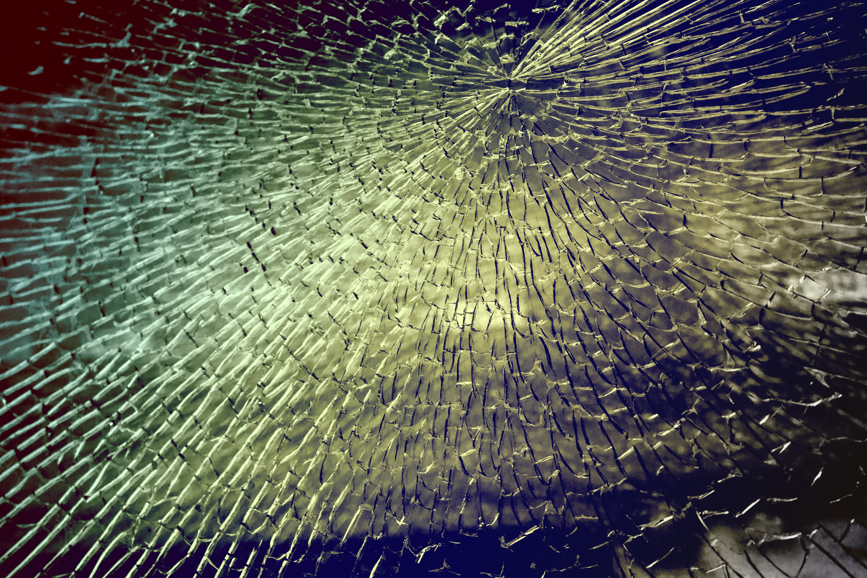 Close-up of a cracked glass surface with light reflecting off the shattered pieces