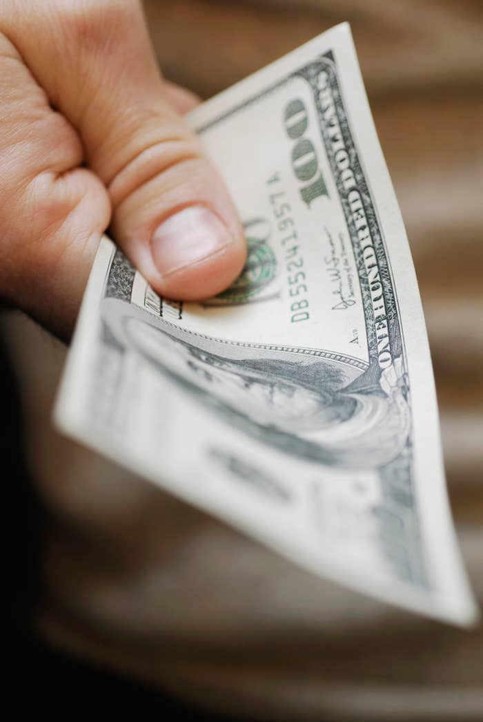 Hand holding a $100 bill