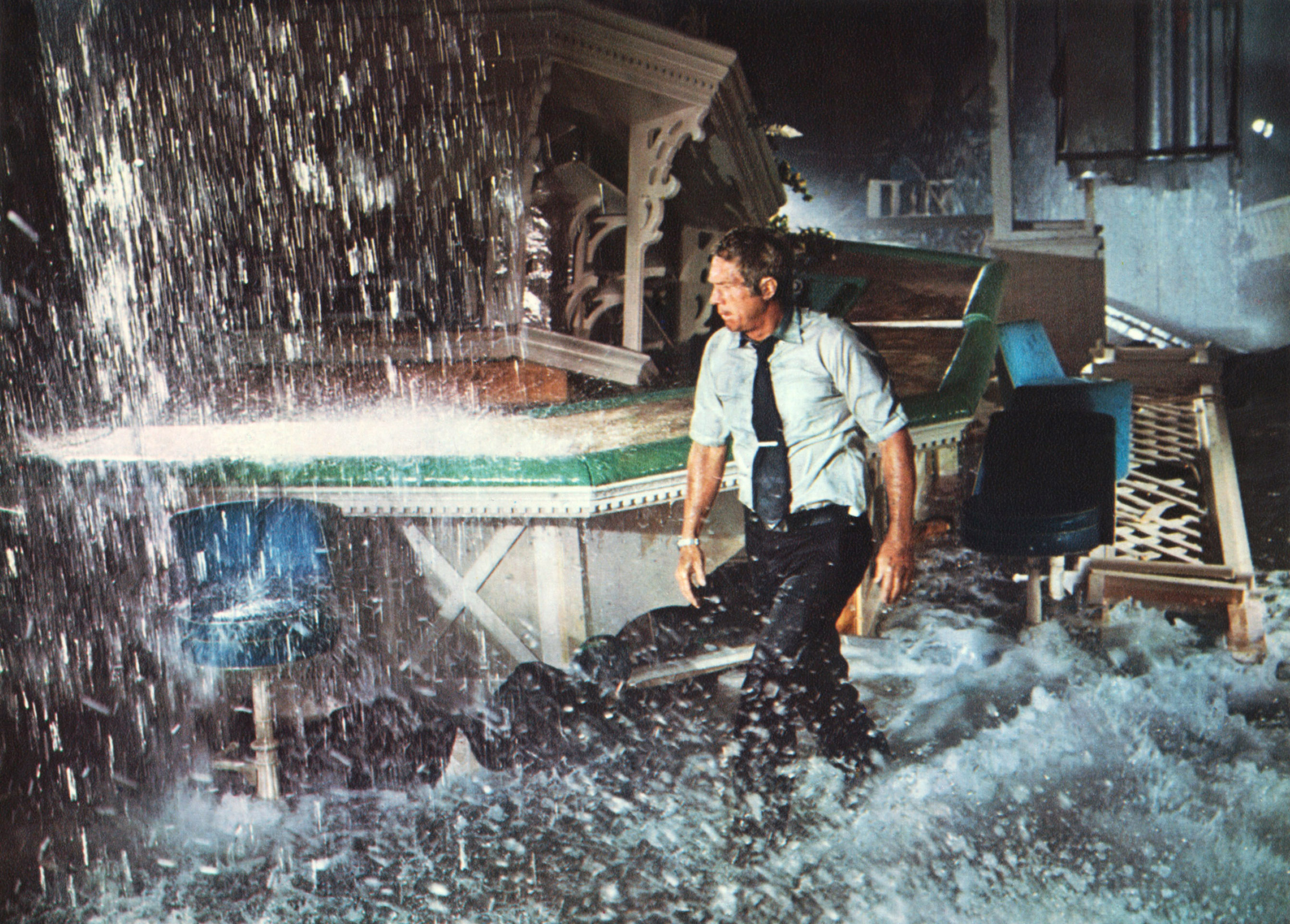 Steve McQueen wears a wet dress shirt and tie in a lavish room flooding with water