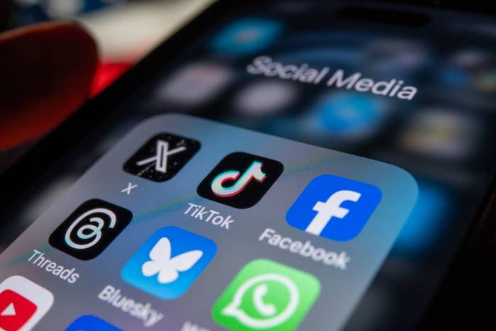 Close-up of a smartphone screen showing social media app icons including X, TikTok, Facebook, Threads, and Bluesky