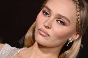 Person with braided hair and gem earrings gazes at the camera, wearing an elegant outfit suitable for a red carpet event