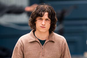 Person wearing a casual brown sweater and jeans walks outdoors