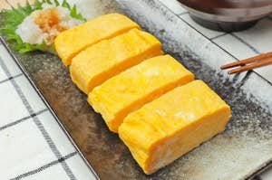 卵焼きが四切れ、皿に盛られている。隣に味噌汁の碗がある。