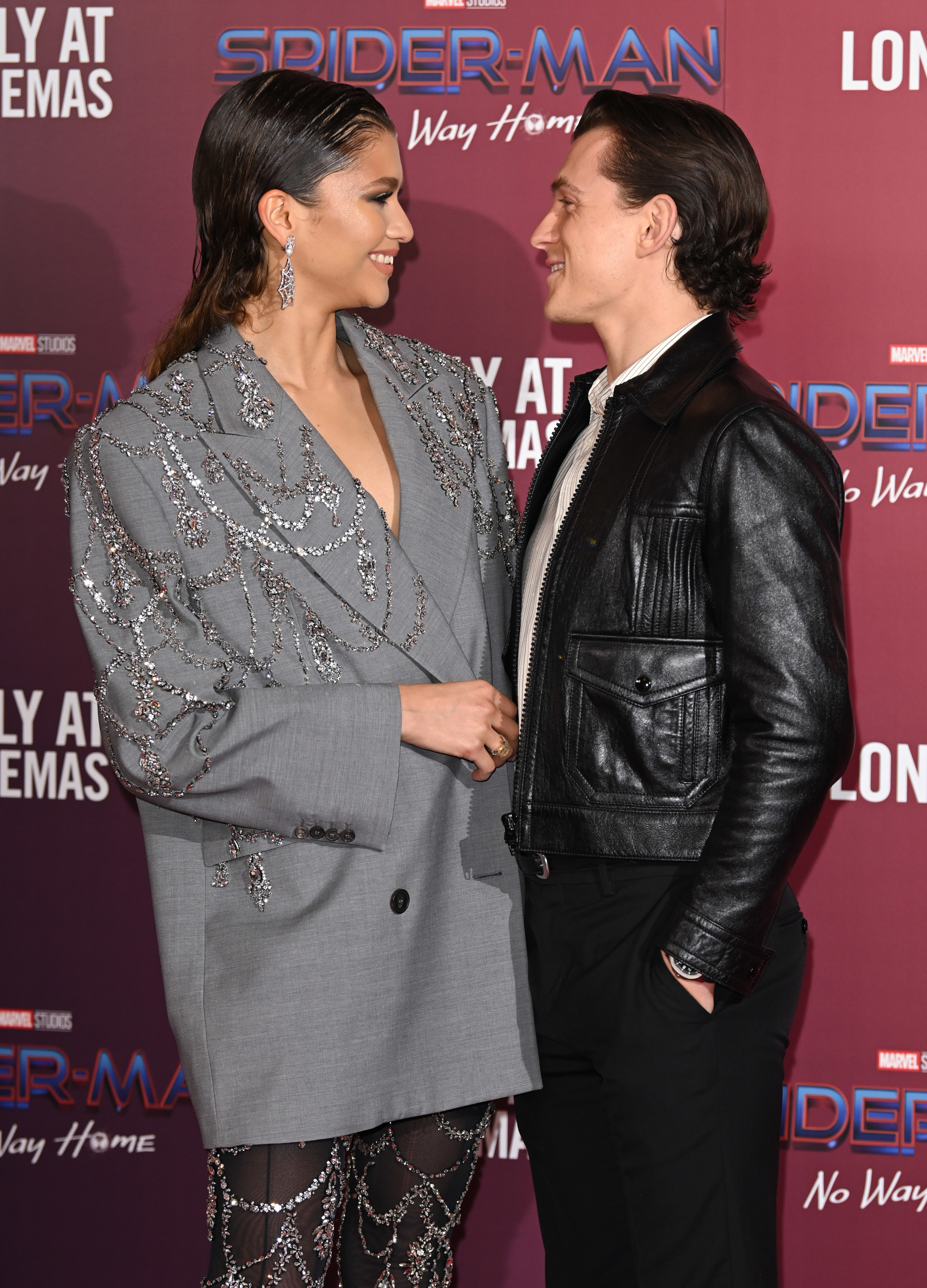 Zendaya and Tom Holland on a red carpet facing each other and smiling