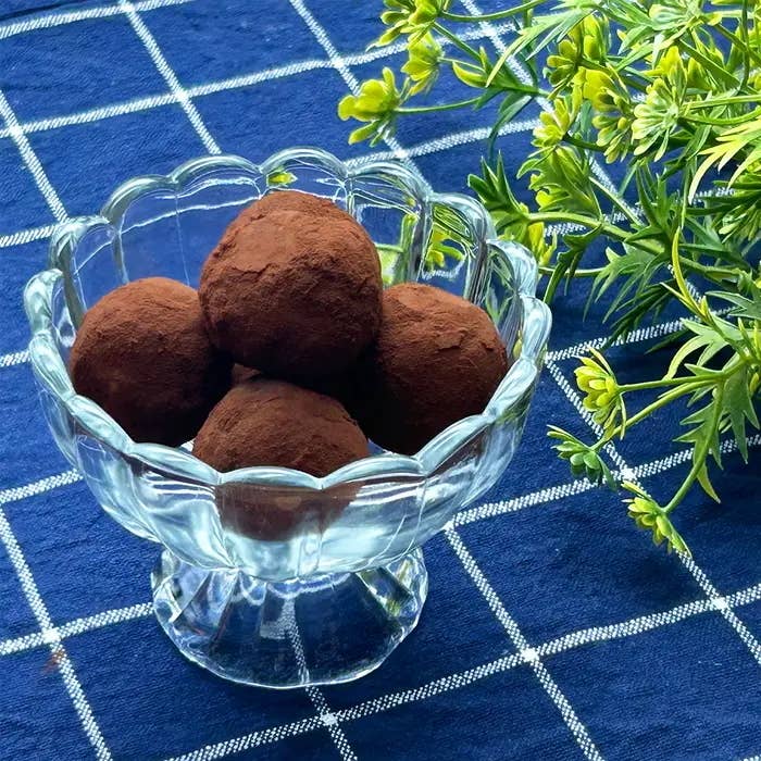 ガラスの器に入ったチョコレートトリュフがテーブルに置かれ、横にグリーンの葉が飾られている。