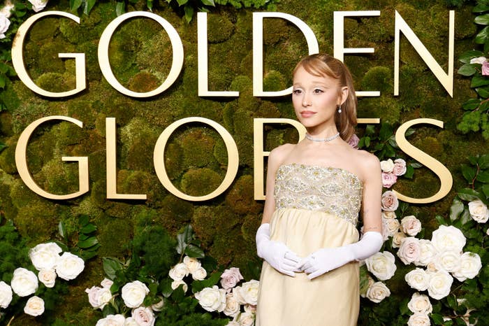 Ariana Grande in elegant gown and gloves poses against a floral backdrop with &quot;Golden Globes&quot; text