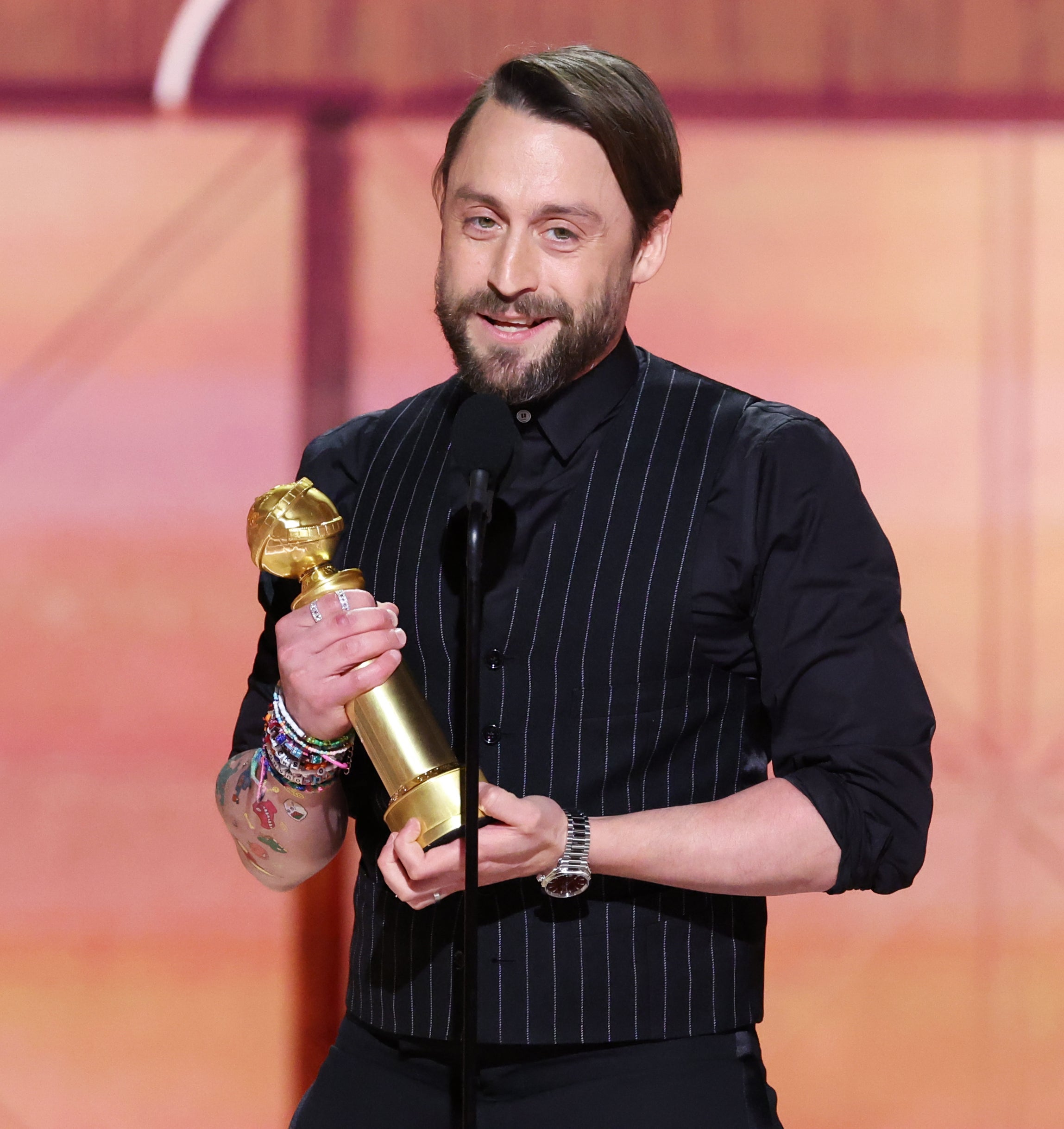 Kieran Culkin holding an award on stage, smiling