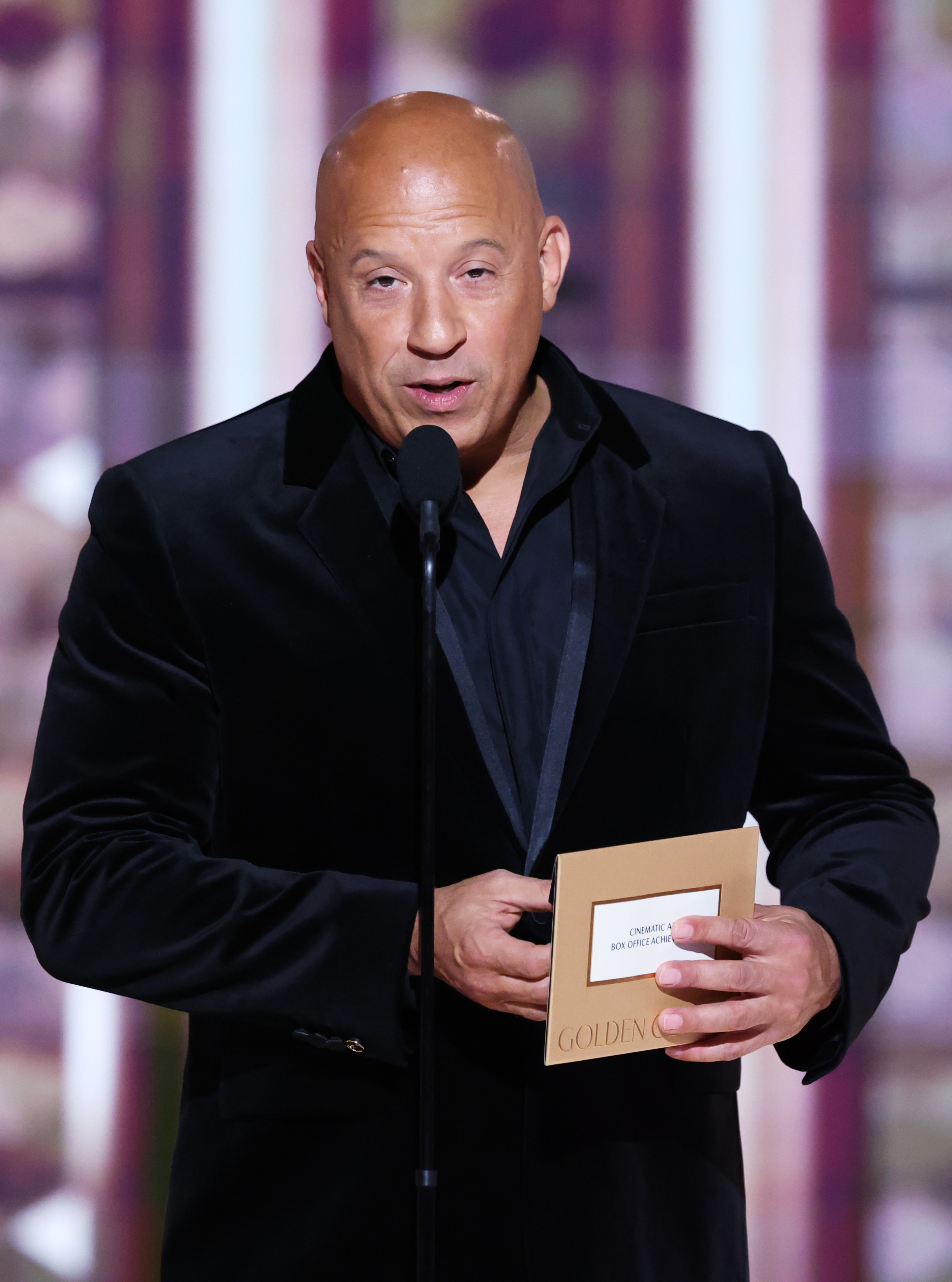 Vin Diesel on stage, speaking into a microphone