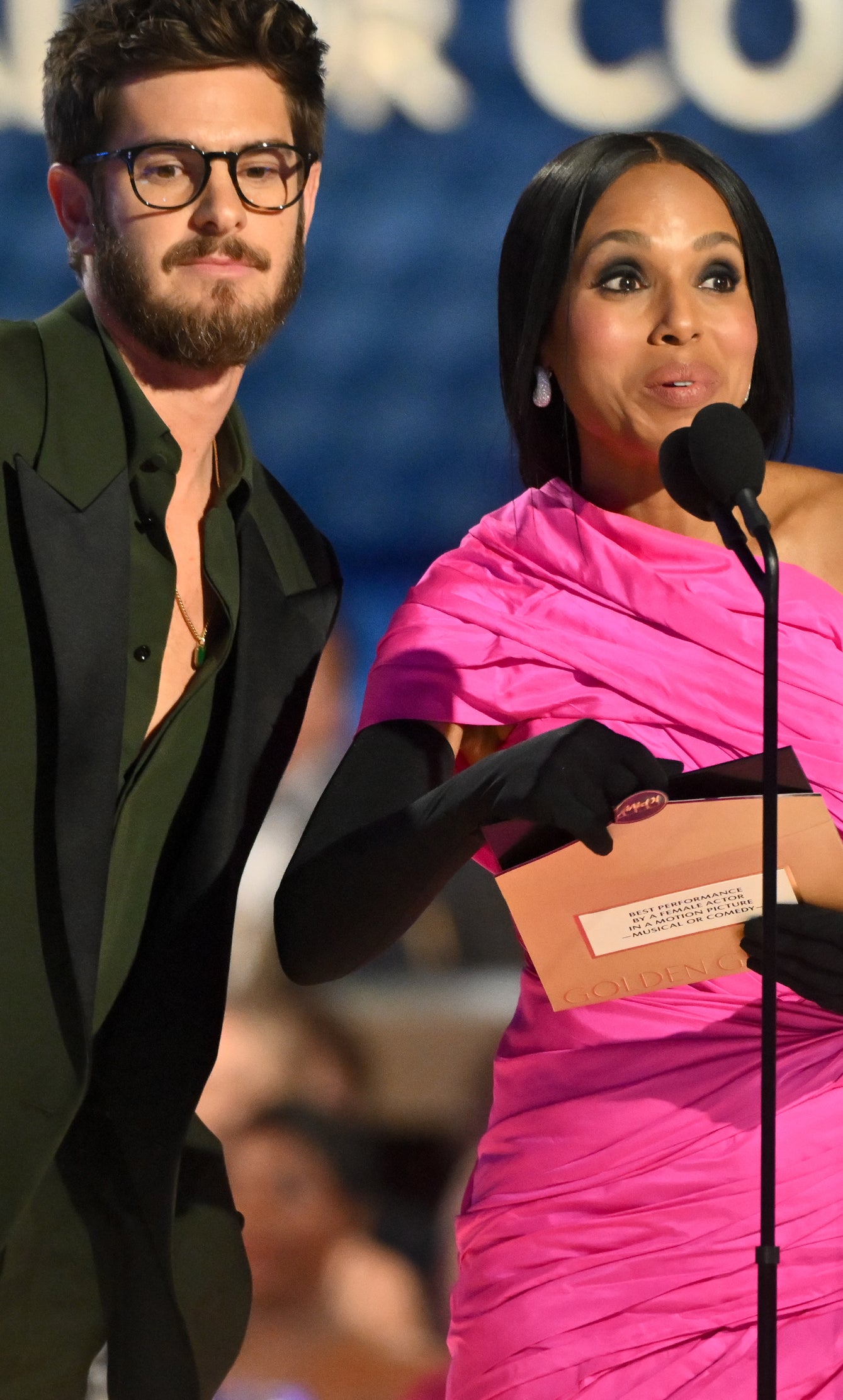 Andrew Garfield in a suit and glasses on stage at the Golden Globes