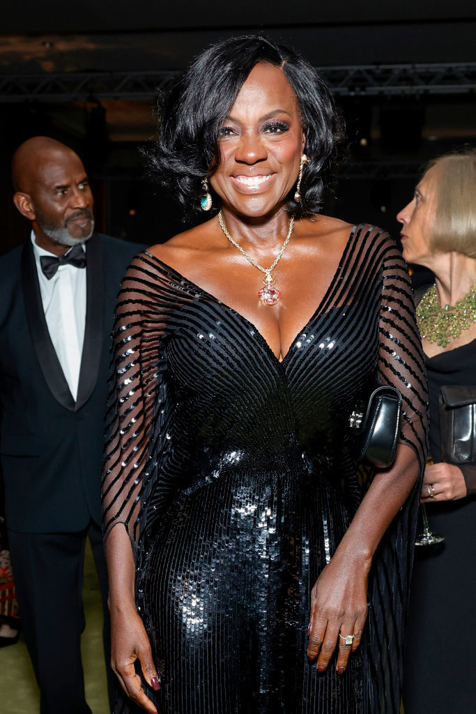 Viola in an elegant sequin gown, smiling at a formal event. Other attendees are visible in the background