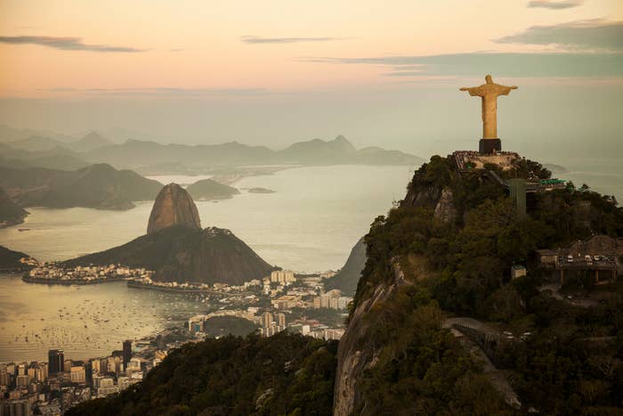 Aerial view of Christ the Redeemer statue overlooking Rio de Janeiro, with Sugarloaf Mountain in the background at sunset