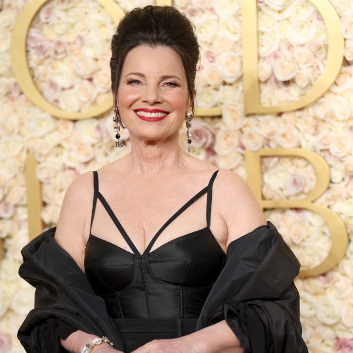 Person in elegant black dress and matching jacket, smiling on a floral background, holding a sparkling handbag