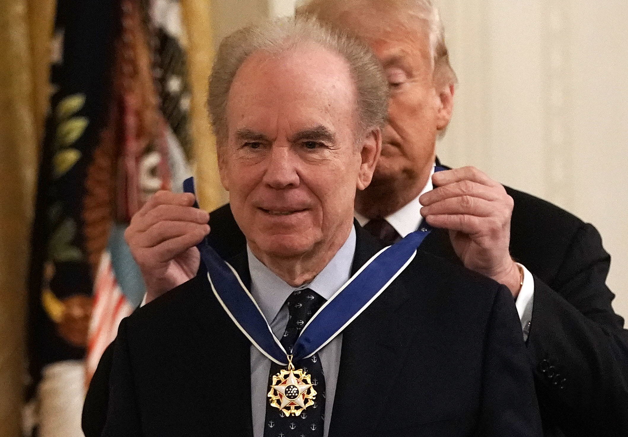 A man receives a medal from another individual during an official ceremony