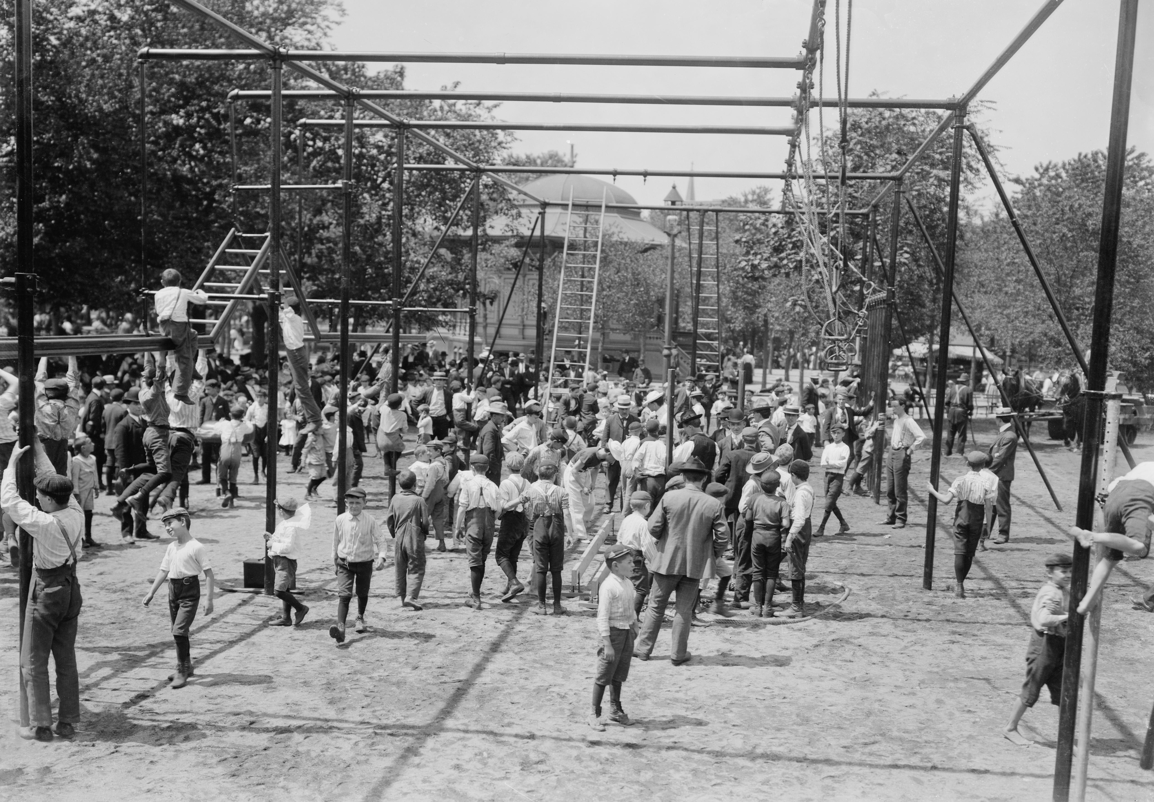 Vintage photo of children and adults at a busy playground with climbing structures and ladders, capturing a lively historical scene