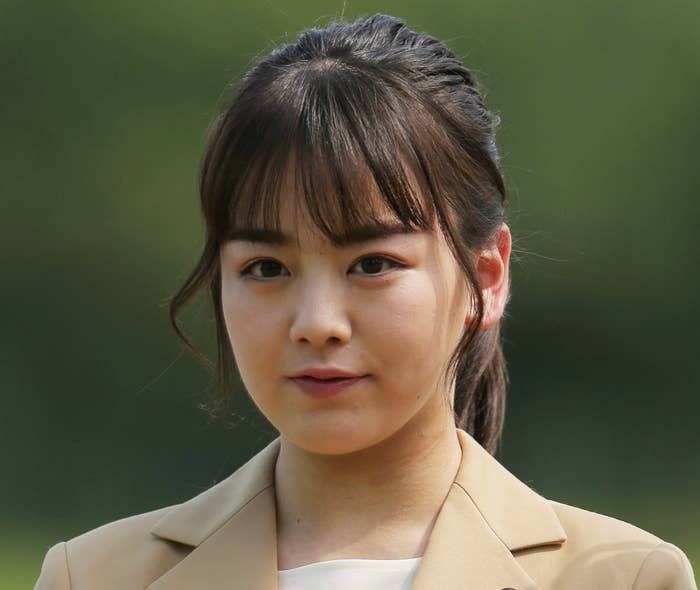 女性がピン付きのブレザーを着てポートレート撮影されています。