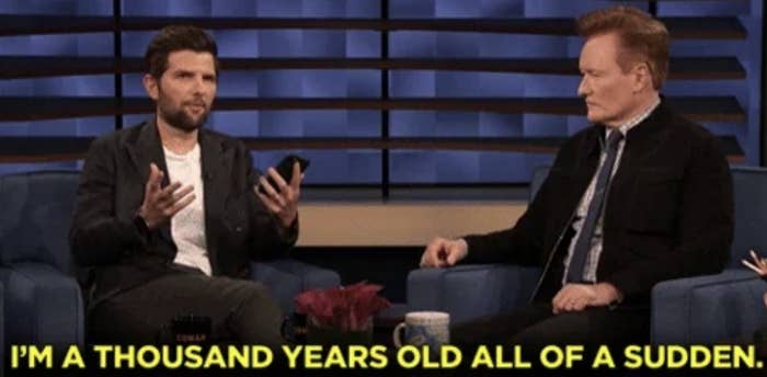Two men talk on a talk show set. One holds a phone, looking expressive. The subtitle reads, &quot;I&#x27;m a thousand years old all of a sudden.&quot;