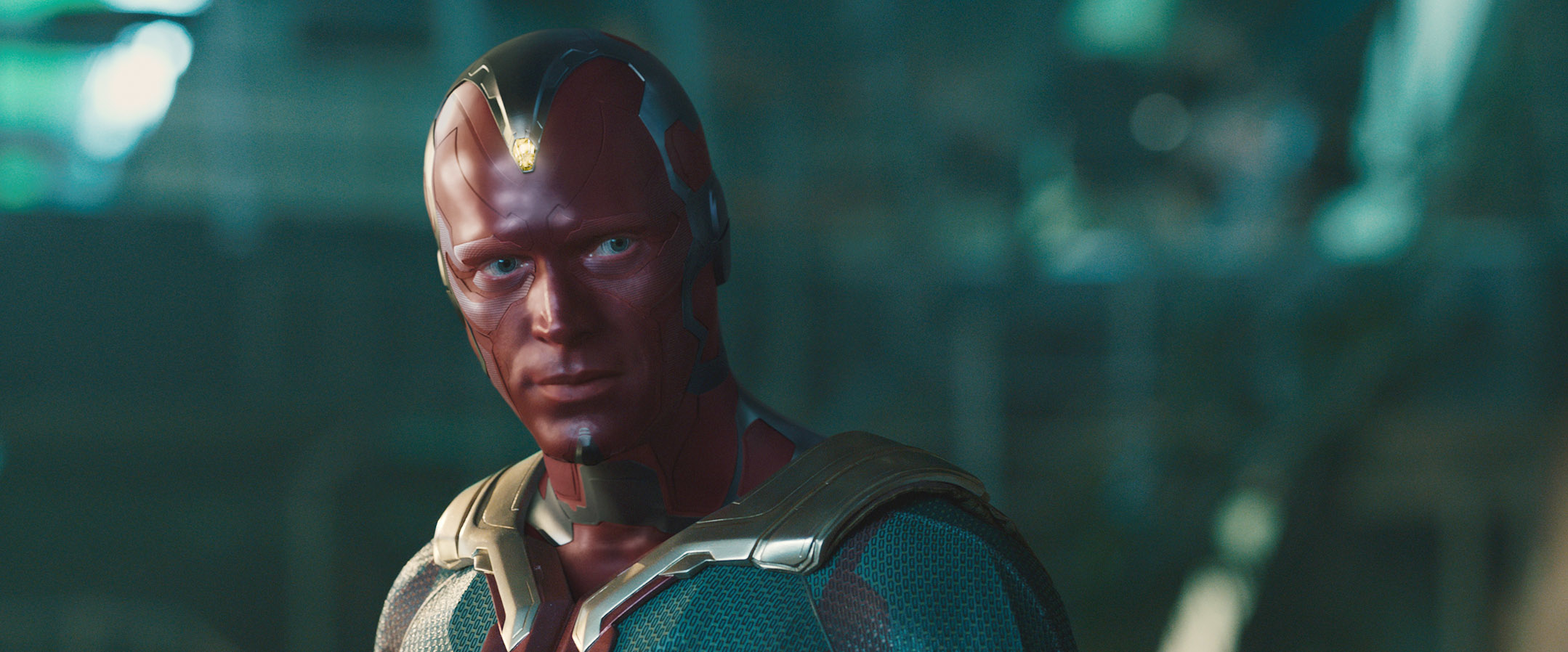 Paul Bettany as Vision in a red futuristic costume with metallic details, looking intently