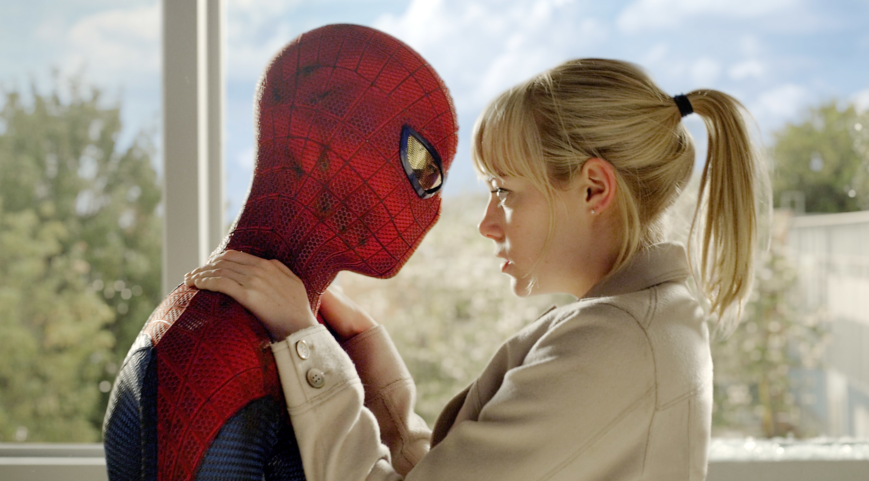 Spider-Man facing a woman holding his shoulders in an emotional scene, indoors with a window view