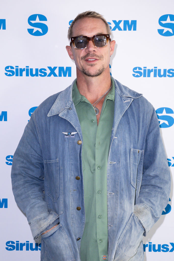 Person in sunglasses wearing a denim jacket over a green shirt, posing in front of a SiriusXM backdrop