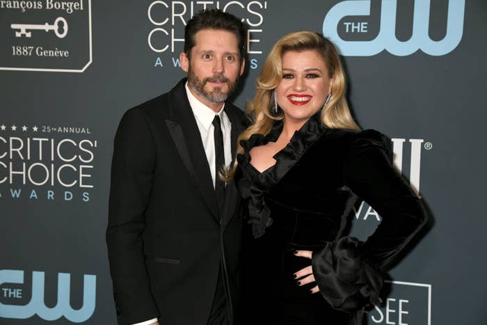 Two people posing on a Critics&#x27; Choice Awards red carpet. The woman wears a black ruffled dress; the man is in a black suit and tie
