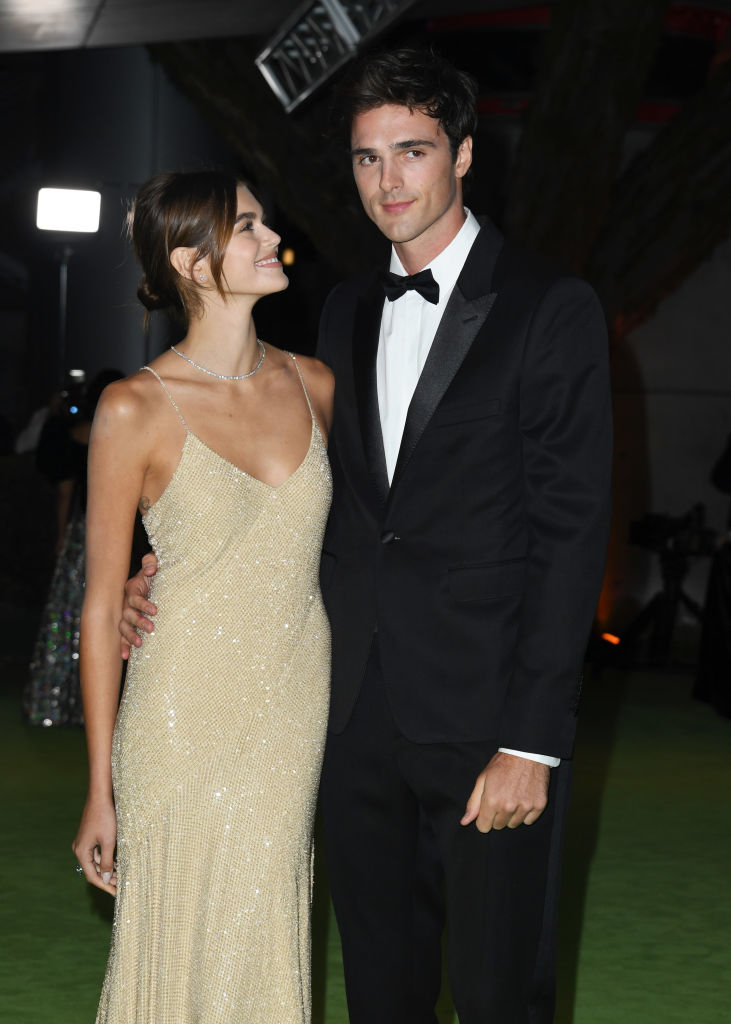 Two people on a red carpet, one in a shimmering gown and the other in a tuxedo, standing side by side