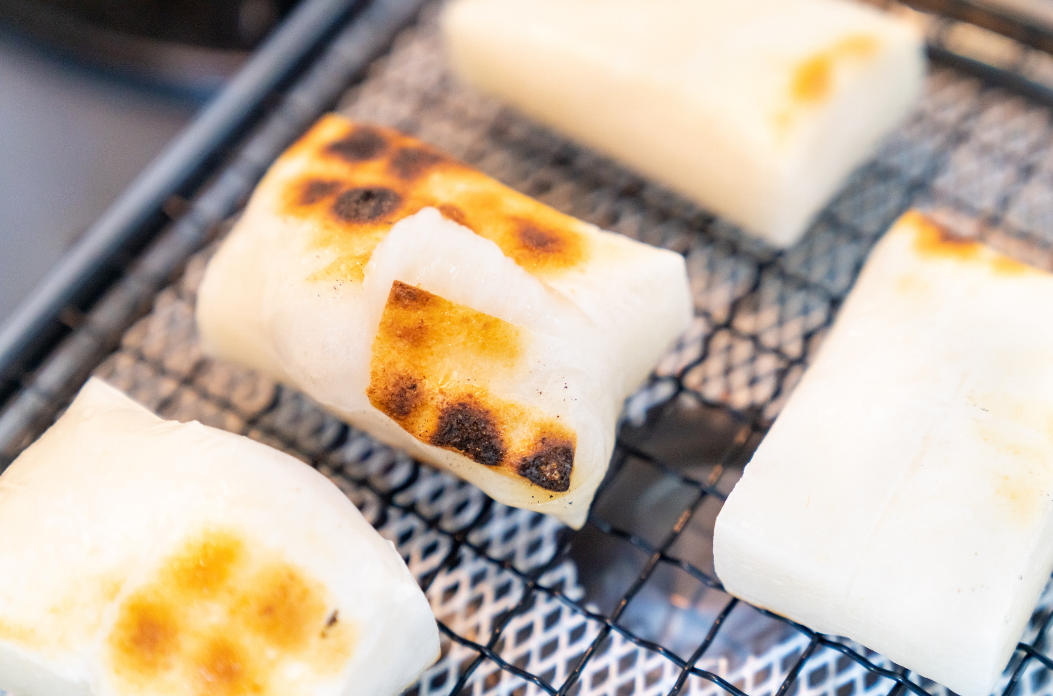 焼き網で焼かれている4つの餅。