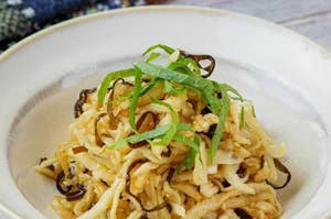 細切り昆布と野菜の和え物が白い器に盛られ、上に刻んだ青じそがトッピングされています。