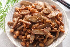 料理皿に盛られたごぼうと大豆の和え物。ごまがかかっている。
