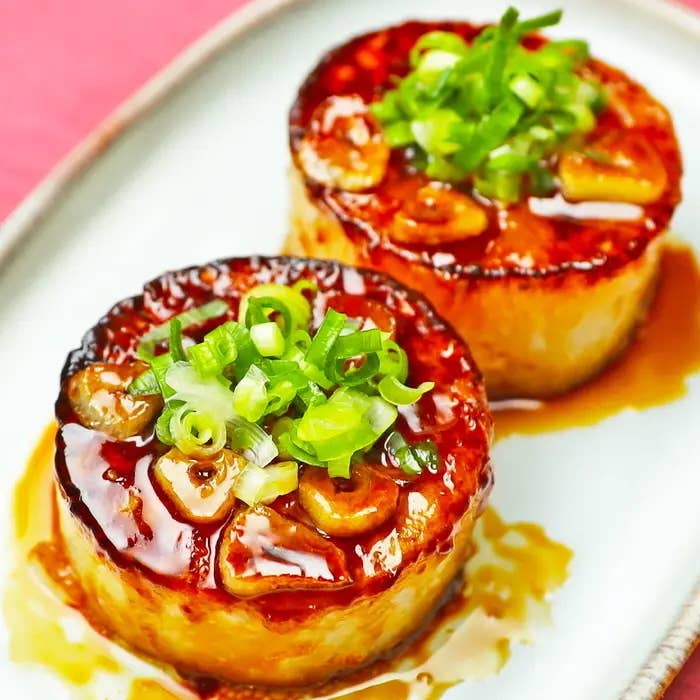 2つの焼いた大根が皿に盛られており、ネギがトッピングされています。