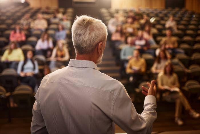 Man with gray hair speaks to a classroom full of seated students