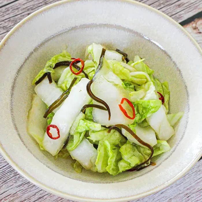 白菜の漬物がボウルに盛られている。海藻と赤唐辛子が添えられた料理。