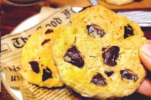 チョコチップクッキーが皿にのっている。背景に新聞紙と青いカップが見える。