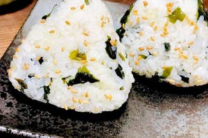 おにぎり2個が皿に乗っている。わかめとごまがトッピングされている。