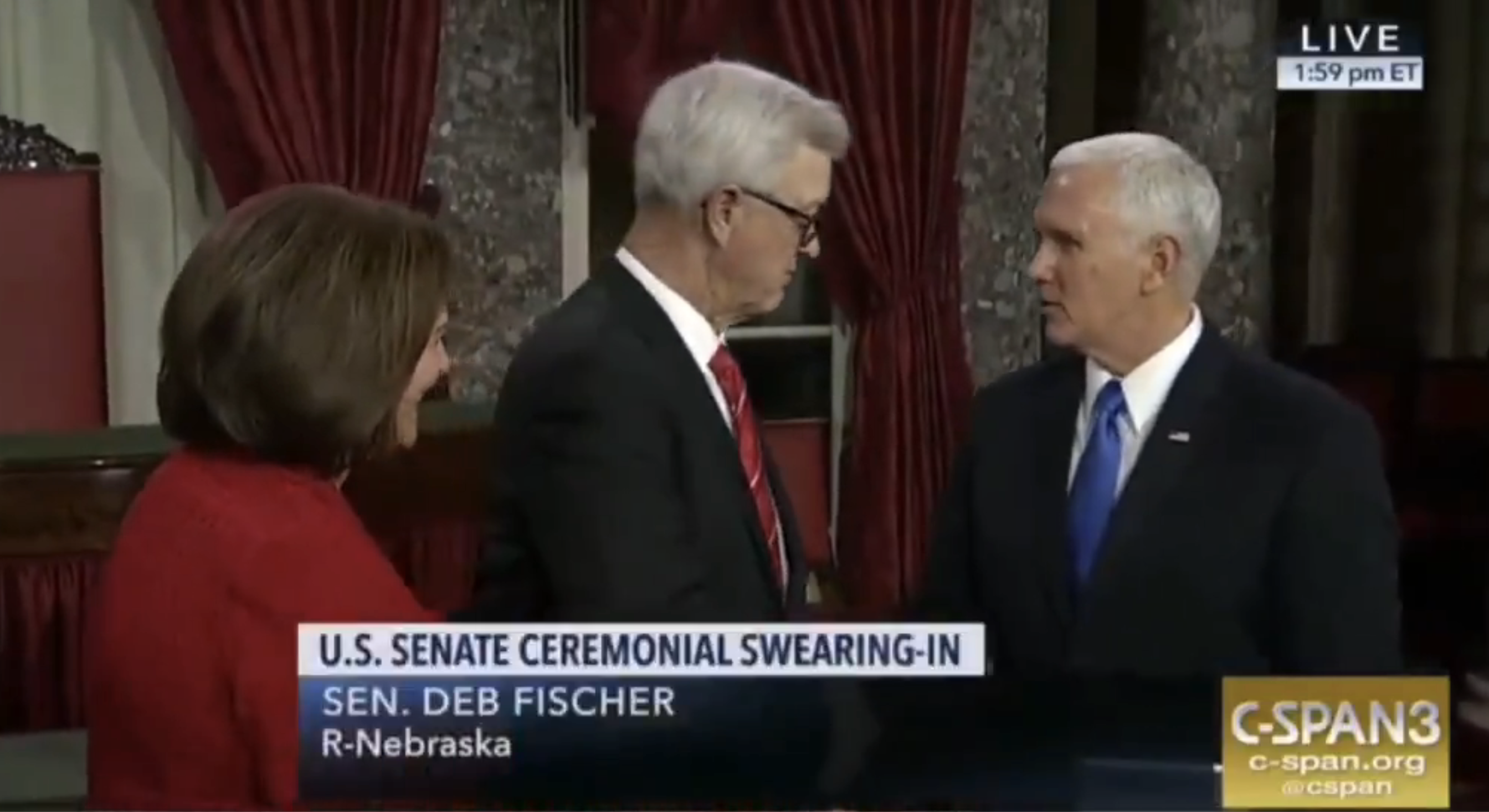 People attending the U.S. Senate ceremonial swearing-in. A man in a suit shakes hands with another in a navy suit and tie. Text on screen identifies location and time