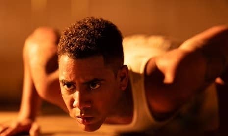 Person in intense focus, wearing a sleeveless top, appears ready for action in a dramatic scene