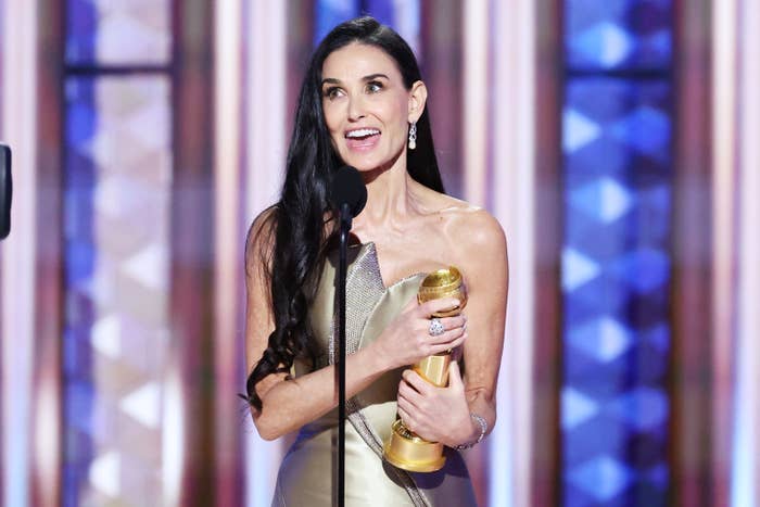 Demi Moore in elegant, strapless gown holding a golden globe